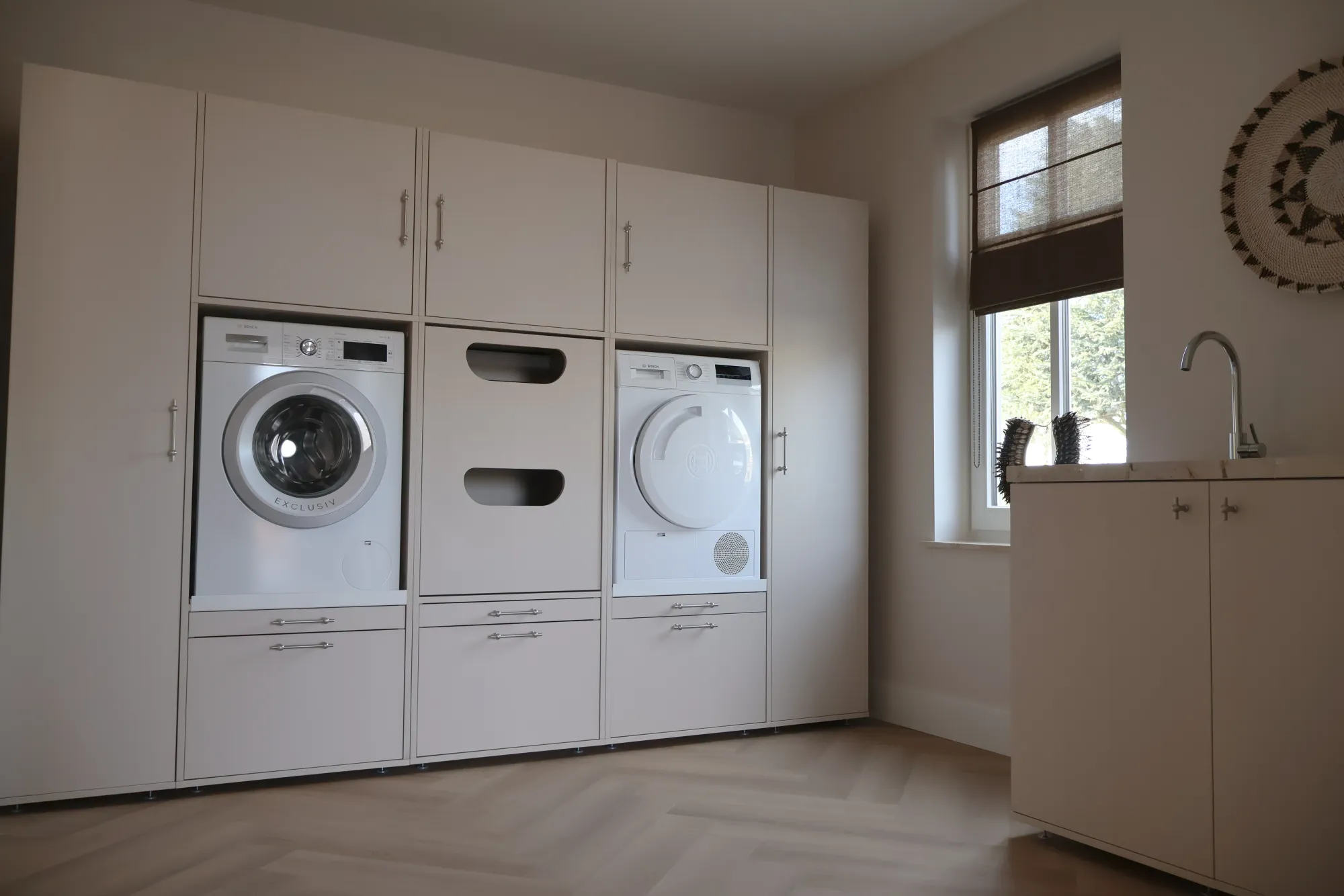 Helle Washtower Schrankwand mit integrierten Geräten und mittigem Wäschekorb