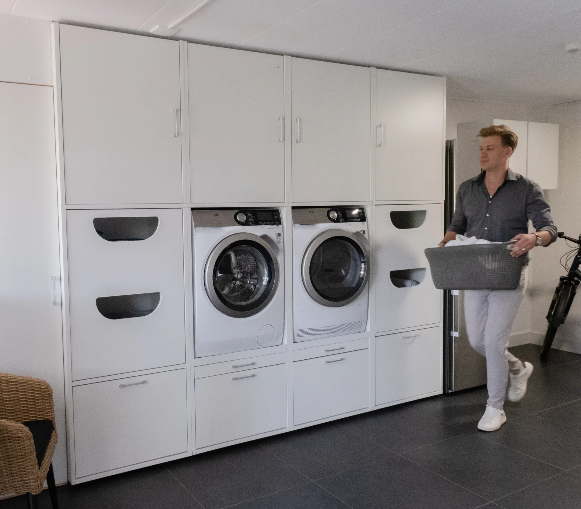 Mann trägt einen Wäschekorb neben einer weissen Washtower Schranklösung